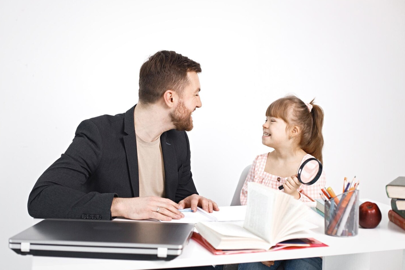 father and little girl with downs reading book together