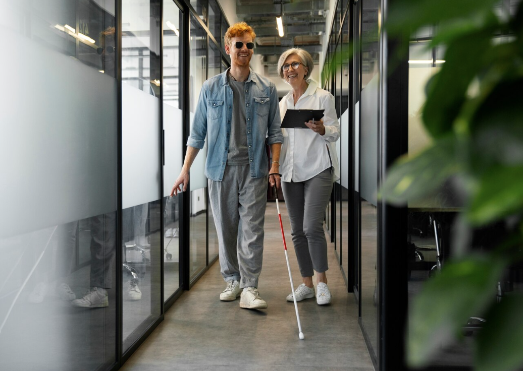 blind man walks with female coworker in office