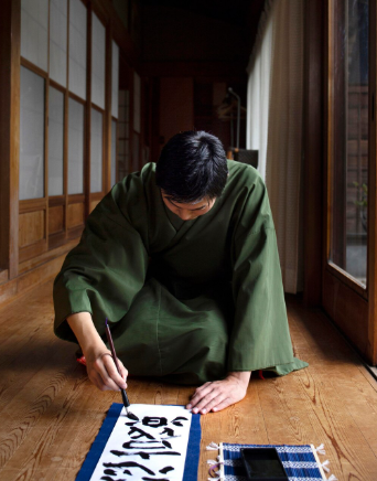 chinese man creating caligraphy in robe