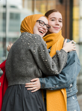 traditionally dressed muslim woman hugging woman in western clothing