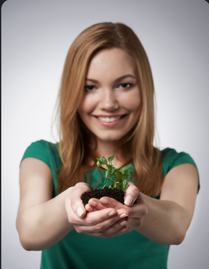 women in green holds plant