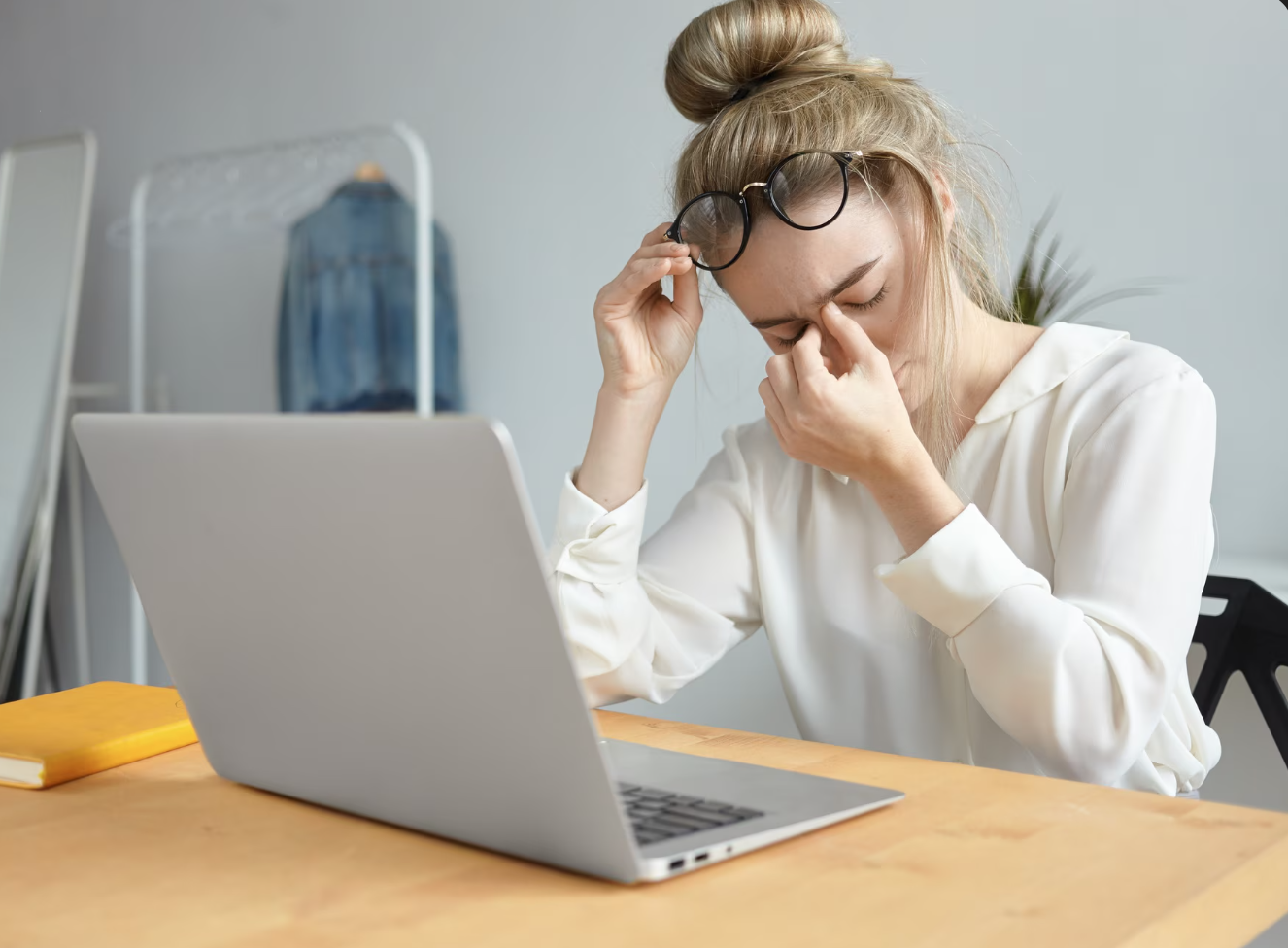 woman rubs eyes at computer