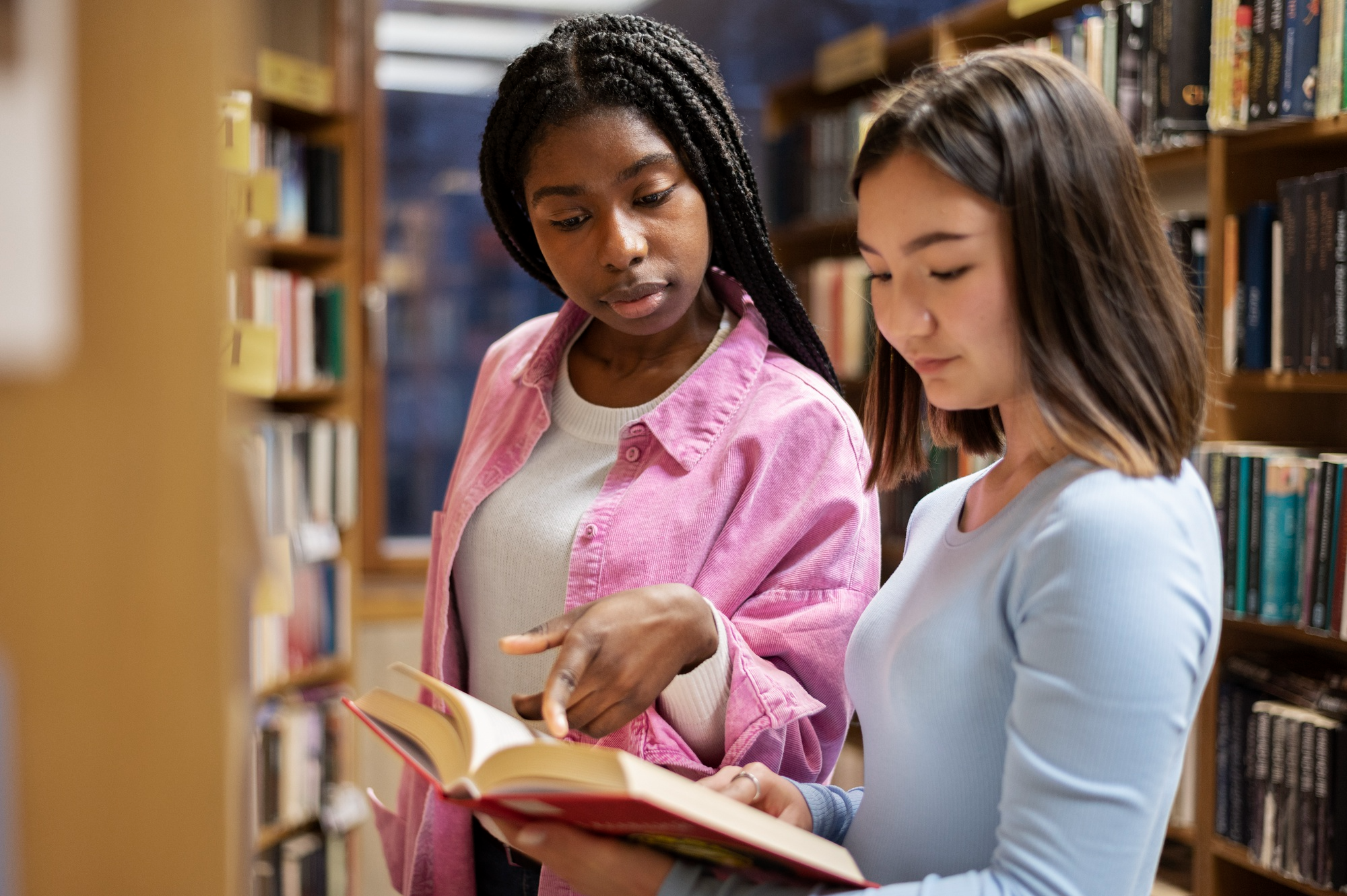 two students help each other in library