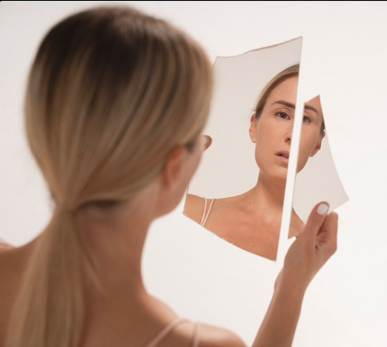 woman looking into broken mirror