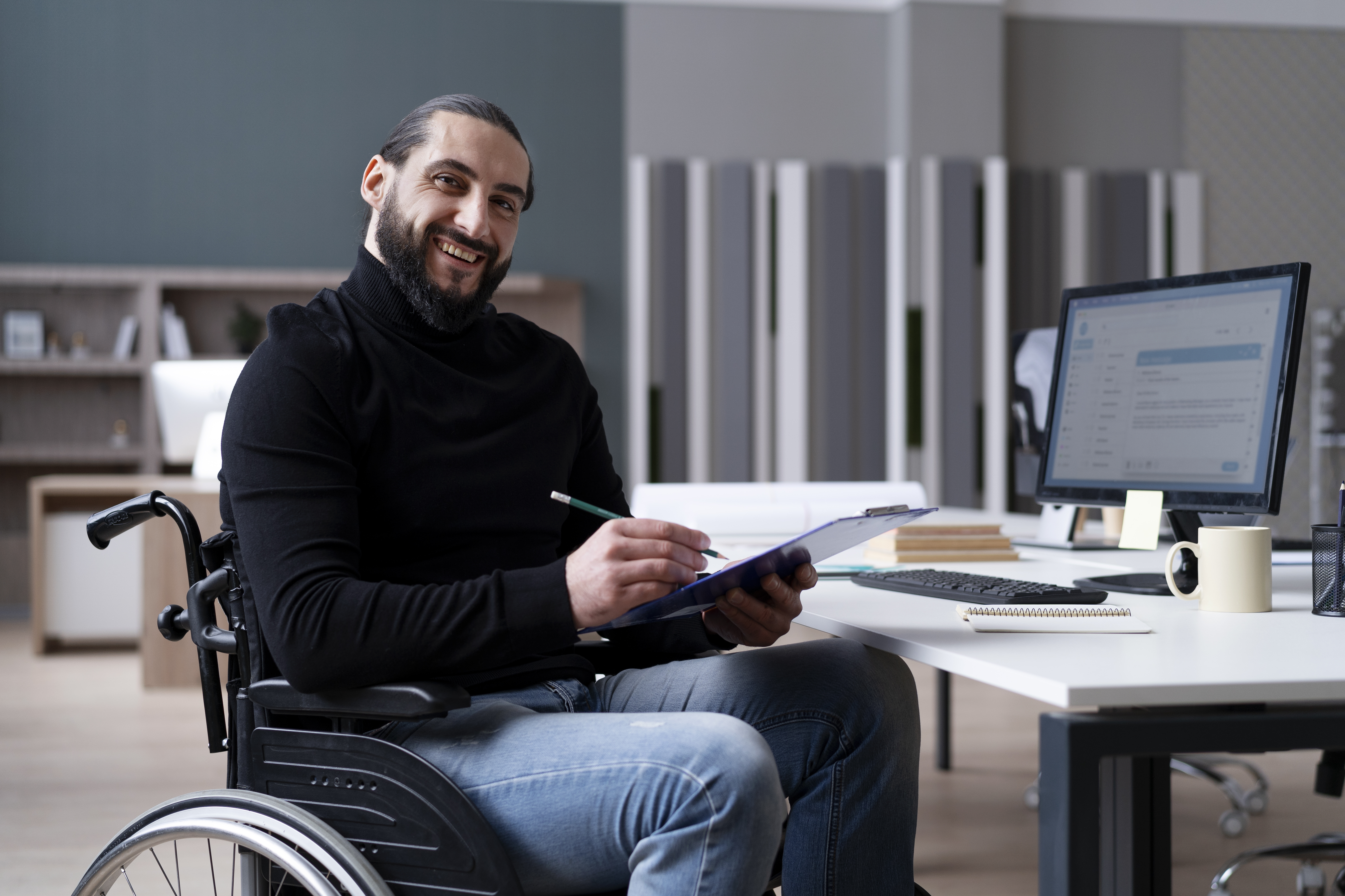 student smiling at desk in wheelchair