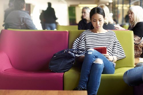 A woman reading something on a tablet in a public space